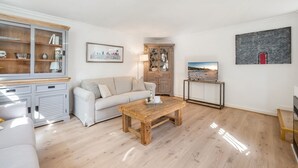 Ein modernes Wohnzimmer mit Couchtisch aus Holz, einem weißen Sofa und einem Holzschrank mit Glastüren.