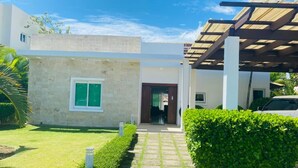 A modern house with a stone facade, a wooden pergola, and a well-maintained lawn. - Rilaxing villa Ocean Village (Sosua)