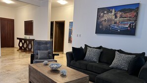 A living room with a wooden coffee table, two sofas, and a painting of a coastal town. - Rilaxing villa Ocean Village (Sosua)