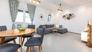 Ein modernes Wohnzimmer mit einem grauen Sofa, einem Holzesstisch mit Stühlen und einem kleinen Beistelltisch.