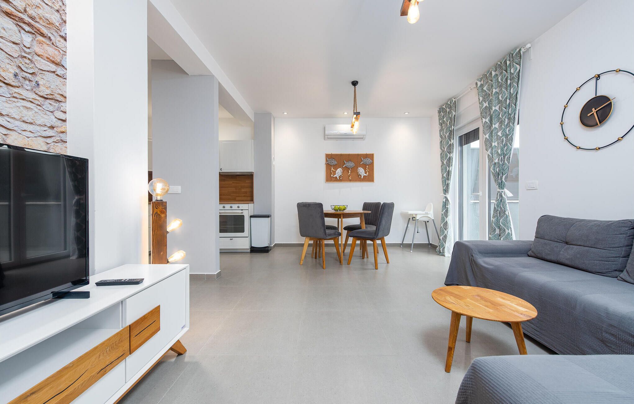 Uma sala de estar moderna com televisão, sofá e área de jantar.