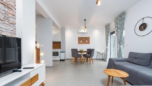 Ein modernes Wohnzimmer mit Fernseher, Sofa und Essbereich.