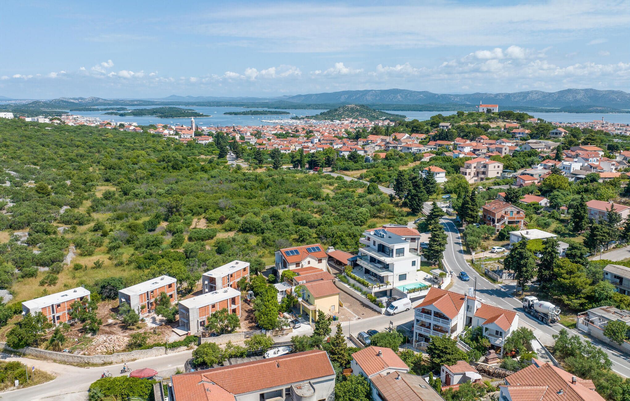 A coastal town with a mix of modern and traditional architecture, featuring a prominent road leading to the sea and a view of the coastline.