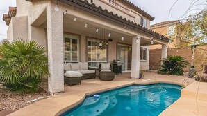 Uma casa com alpendre coberto, piscina e mobiliário de exterior.