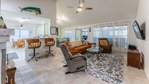 A spacious living area with a sofa, armchairs, a coffee table, and a ceiling fan. - Private Hot Tub, Stone Floors, Tall Fenced Yard, Fire Pit, & BBQ Grill (Grand Prairie)