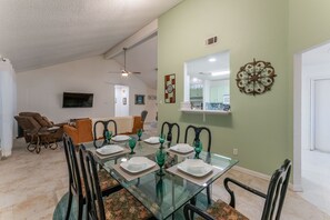 Un coin repas avec une table en verre, dressée pour quatre personnes, entourée de chaises.
