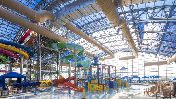 An indoor water park with multiple slides and a large open space. - Private Hot Tub, Stone Floors, Tall Fenced Yard, Fire Pit, & BBQ Grill (Grand Prairie)