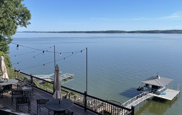 A lakeside deck with tables and chairs, a gazebo, and a dock with a small boat. - Lake life at its best, Home on Ky Lake.  Amazing Sunrises! Near Moors Resort. (Gilbertsville)