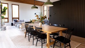 A modern dining area with a wooden table, black chairs, and pendant lighting.