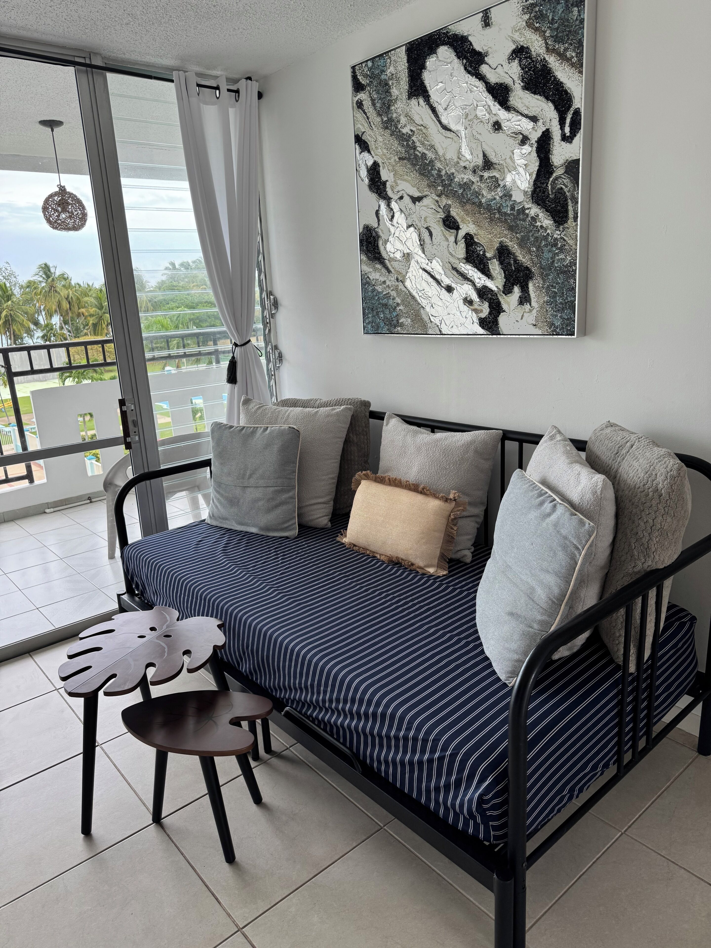 A modern living room with a sofa, pillows, a table, and a large abstract painting.