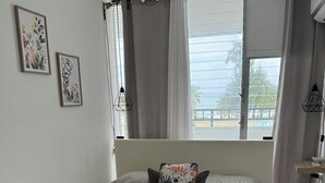 Een opgemaakt bed met een bedsprei met dessin, een decoratief kussen en een paar witte handdoeken.
