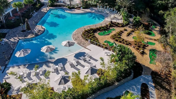 Ein Schwimmbecken mit Liegestühlen und ein Golfplatz.