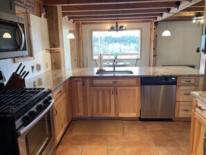 A kitchen with wooden cabinets, a stainless steel dishwasher, and a granite countertop. - ^^PeakViewCabin, Amazing Views w/ Hot Tub 5 min from town-Peaceful and QUIET (Woodland Park)