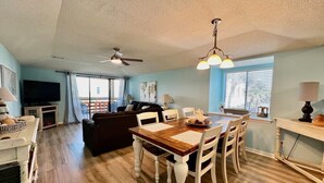 A spacious living area with a dining table, chairs, a sofa, and a ceiling fan.