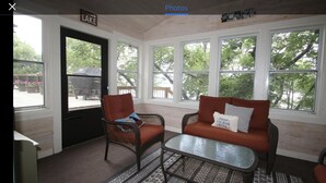 A sunroom with wicker furniture, a glass coffee table, and large windows offering a view of the outdoors. - Cabin with amazing views, prime location and privacy! 3 bedrooms 2 bathrooms (Battle Lake)