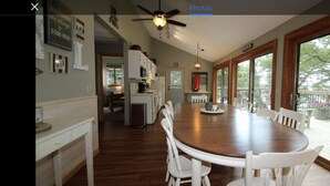 A spacious kitchen with a large wooden table and white chairs, a ceiling fan, and a view of a deck with potted plants. - Cabin with amazing views, prime location and privacy! 3 bedrooms 2 bathrooms (Battle Lake)