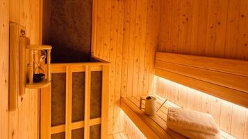 A wooden sauna with benches, a towel rack, and a clock on the wall.