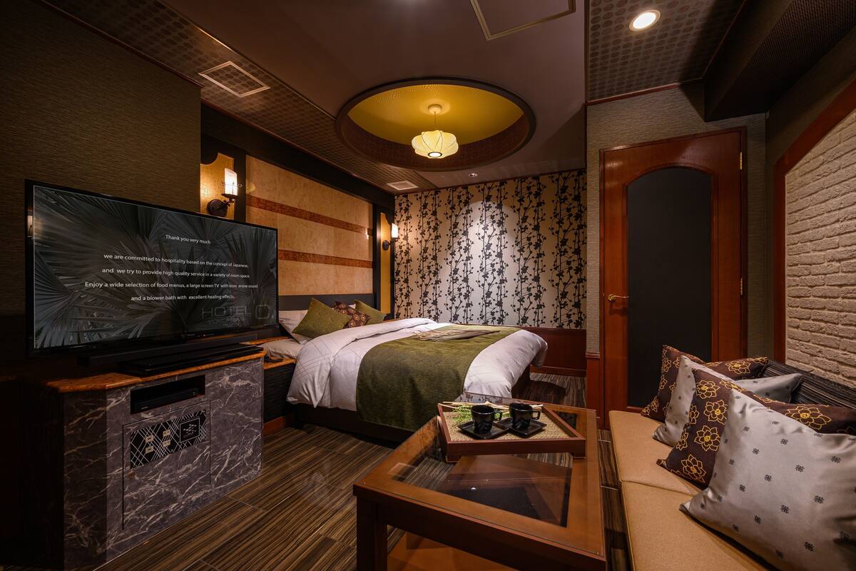 A hotel room with a bed, a television, a coffee table, and a door.