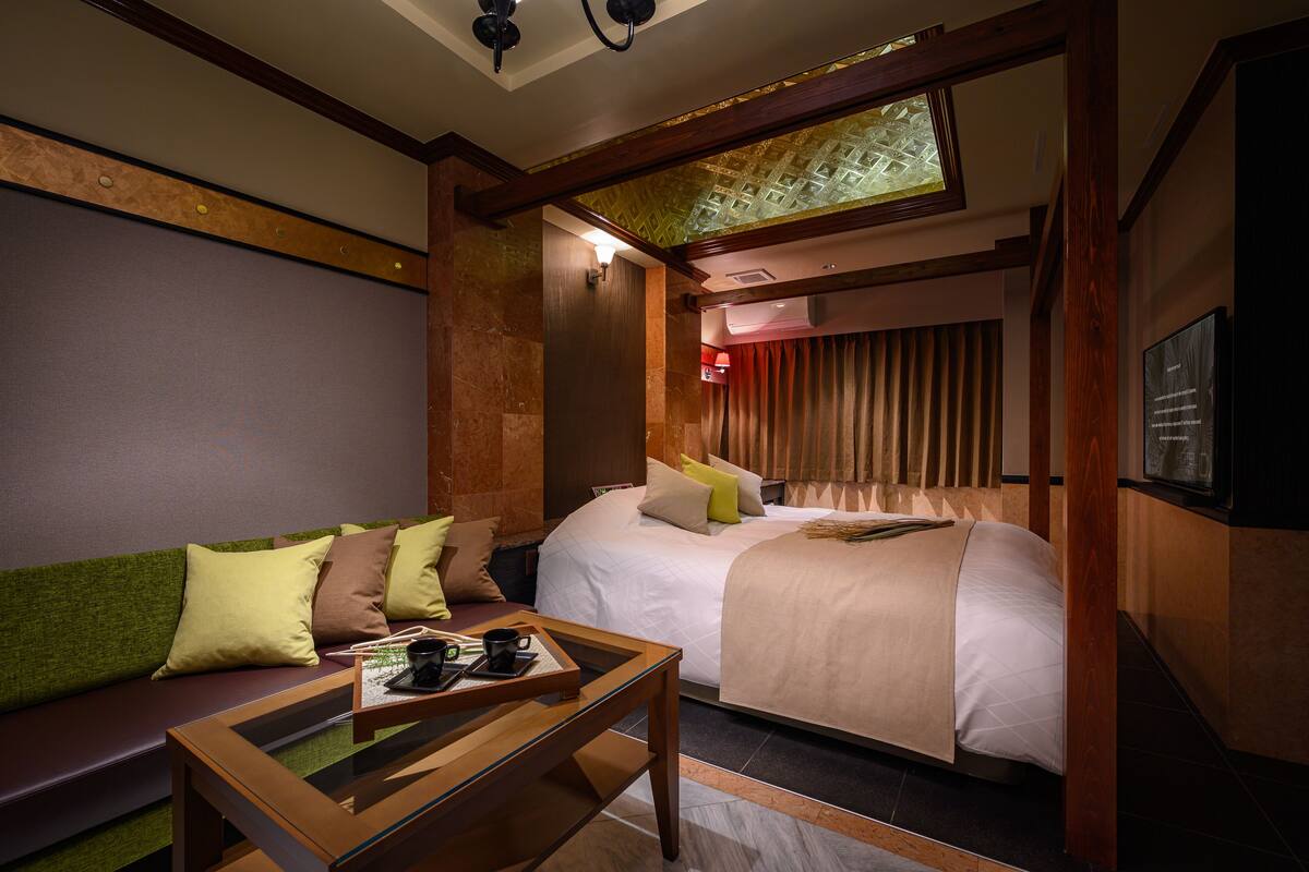 A hotel room with a bed, a sofa, a coffee table, and a TV.
