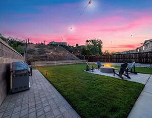 A backyard with a barbecue grill, outdoor seating, and a fire pit.