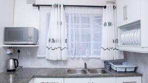 Una cocina con microondas, lavaplatos y escurreplatos.