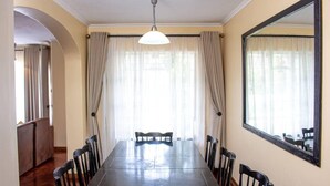 Un comedor con una mesa larga, seis sillas, una lámpara en el techo y un espejo grande en la pared.