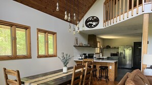 Une cuisine spacieuse dotée de meubles en bois, d’un îlot central et d’un coin repas avec une table et des chaises en bois au style rustique.