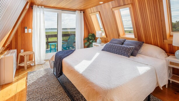Un dormitorio con una cama grande, techo de madera y vistas al exterior.