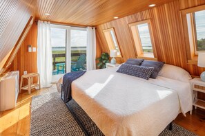 Un dormitorio con una cama grande, techo de madera y vistas al exterior.