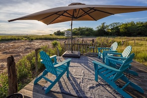 A wooden deck with two turquoise Adirondack chairs and a large umbrella. - Breathtaking Sunsets on Plum Island at Blue Moon (Newbury)