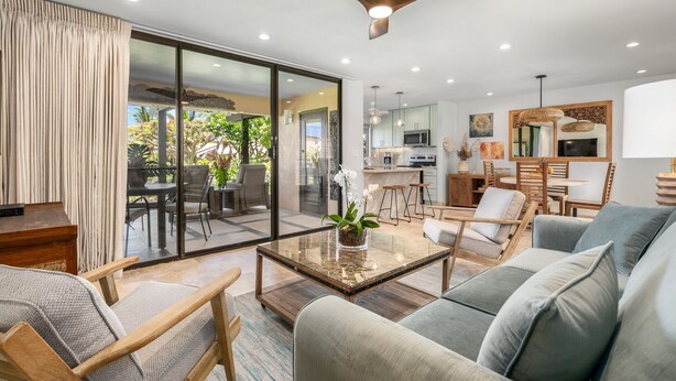 A spacious living room with a glass coffee table, a sofa, and a dining area with chairs.