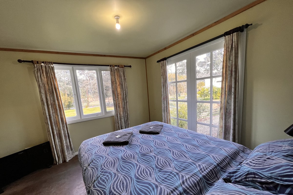 Un dormitorio con dos camas, ventanas amplias y una lámpara en el techo.