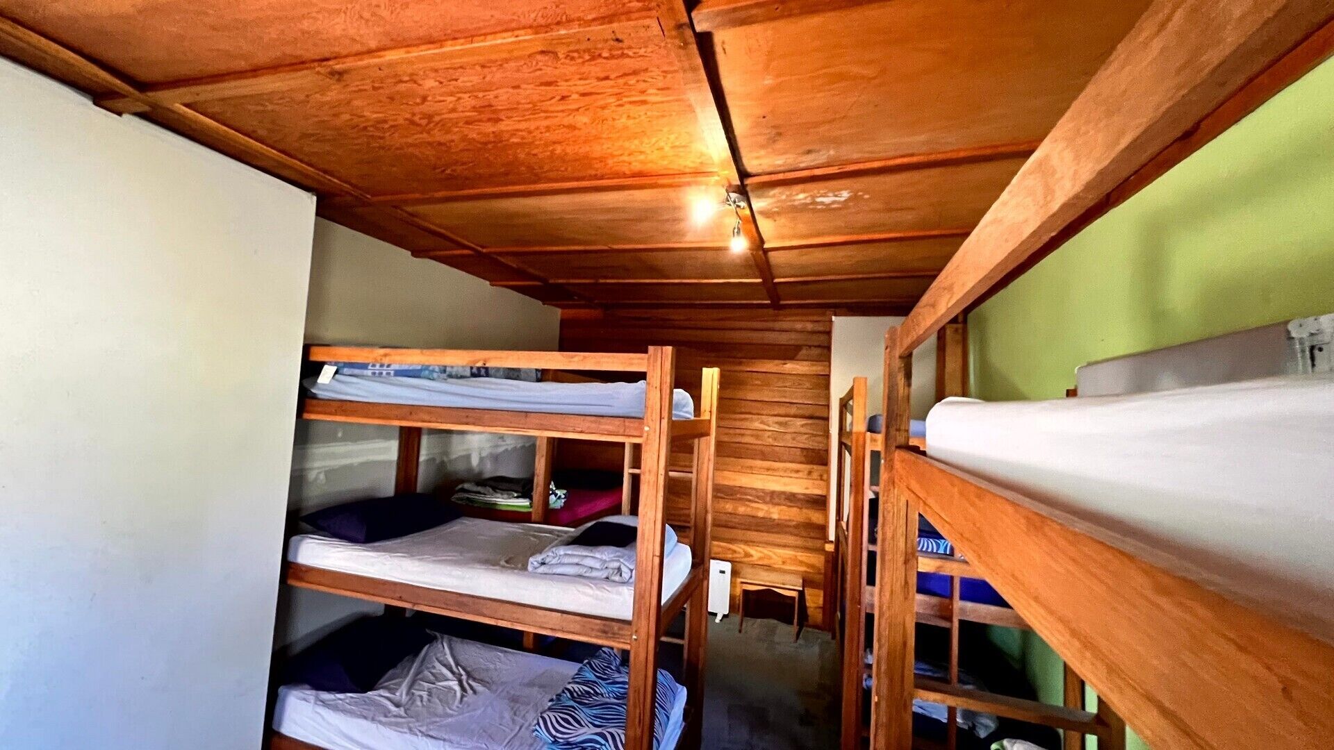 Habitación pequeña con literas, paredes de madera y una mesita.