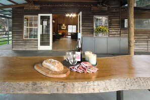 Une cabane rustique en bois, avec un coin repas comprenant une table en bois, une miche de pain, des verres à vin et des bougies.
