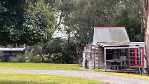 A rustic cabin with a metal roof, surrounded by lush greenery and trees.