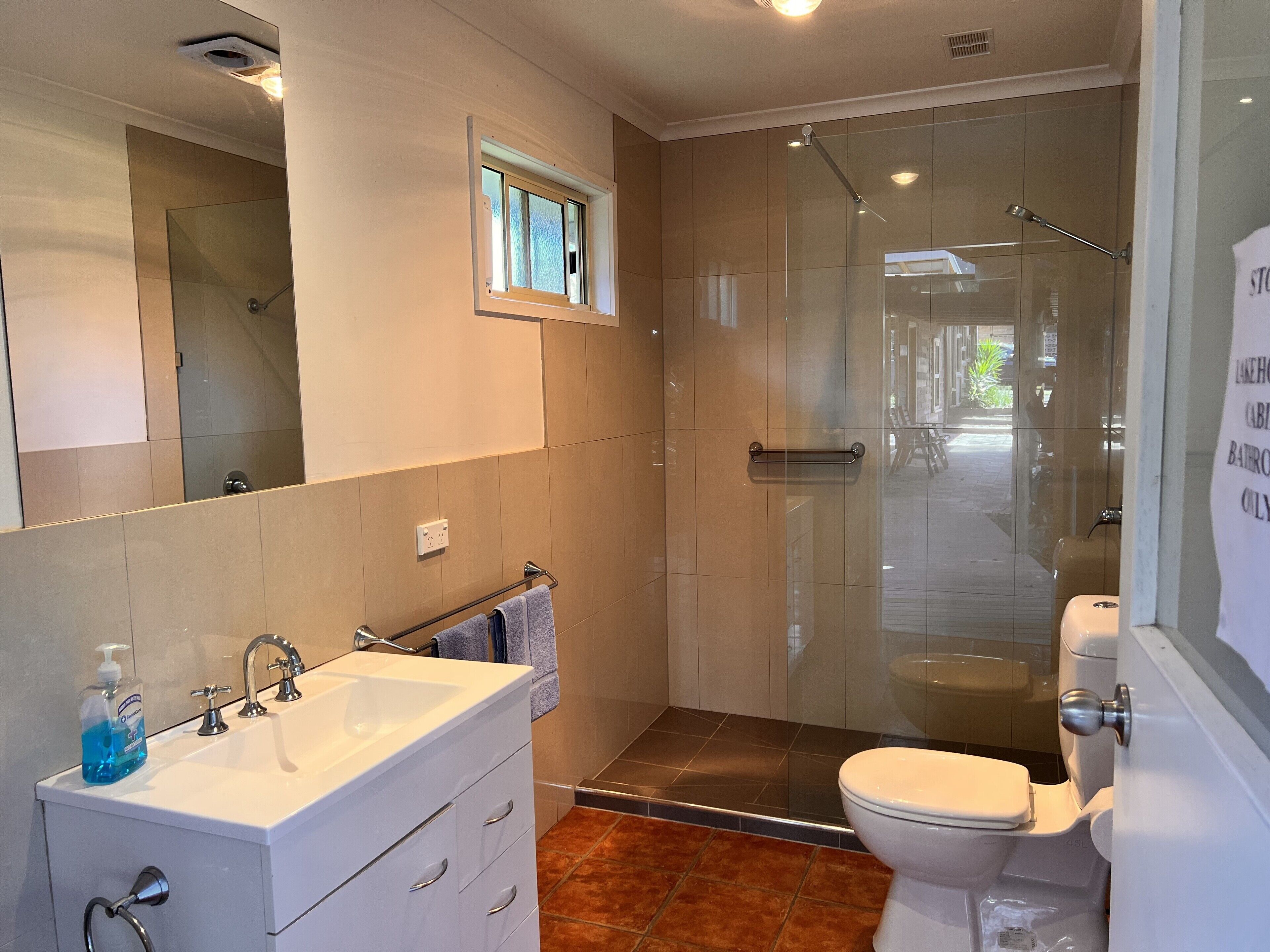 A modern bathroom with a glass shower enclosure, a white sink with a mirror, and a toilet.