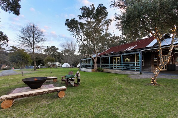 Un espace extérieur rustique avec une terrasse en bois, un foyer et un coin salon abrité.