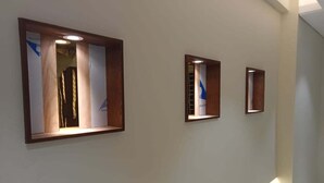 A hallway with three framed pictures on the wall, each with a wooden frame and illuminated from below. - Oasis Hotel Cumilla (Comilla)