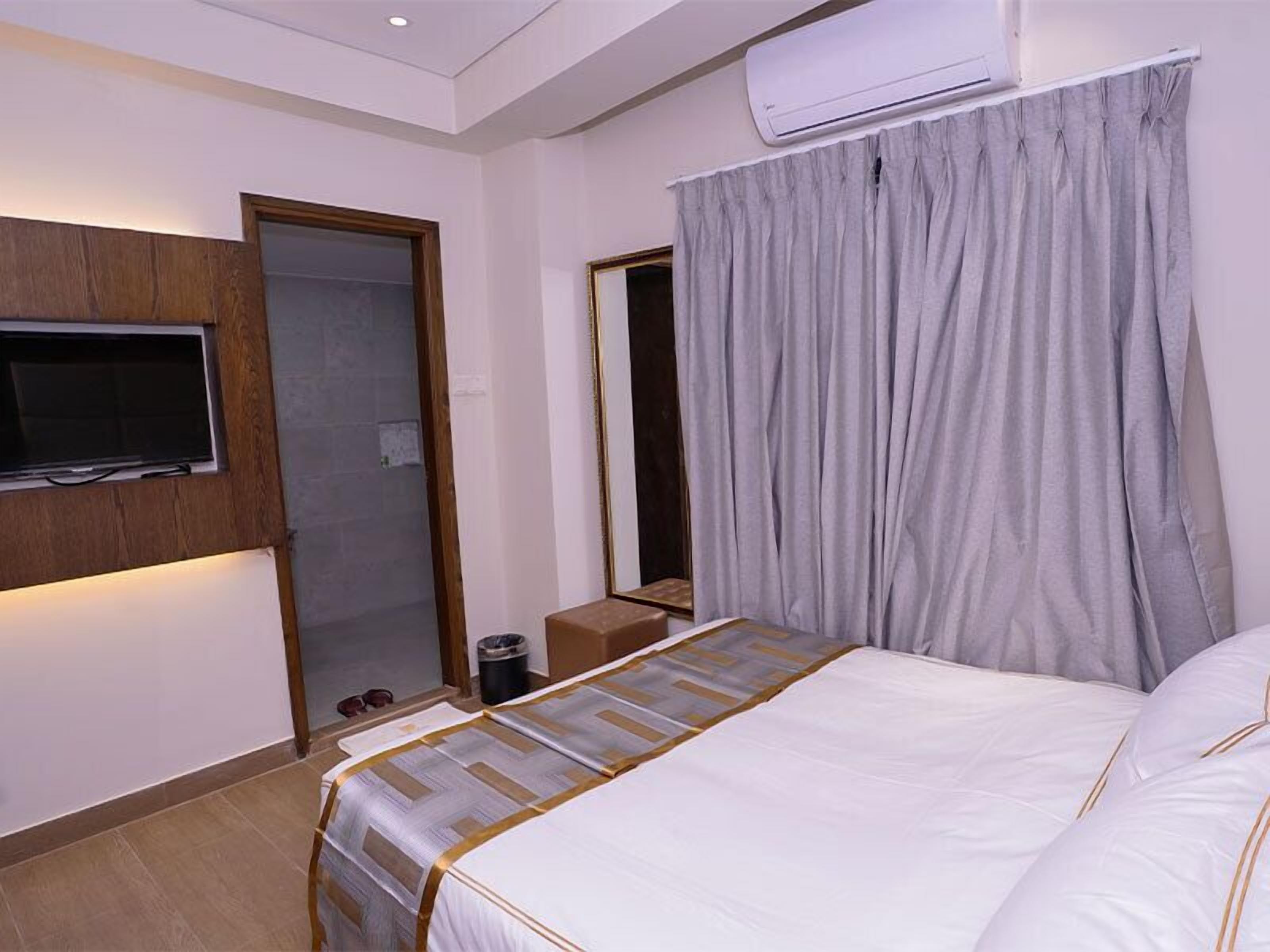 Une chambre d’hôtel équipée d’un lit, d’un téléviseur fixé au mur, d’un miroir et d’un appareil de climatisation.