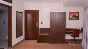 A modern office space with a wooden desk, a chair, and a large wardrobe. - Oasis Hotel Cumilla (Comilla)