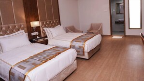 A hotel room with two beds, a wooden headboard, a nightstand with a lamp, and a bathroom visible through an open door. - Oasis Hotel Cumilla (Comilla)