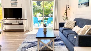 Ein modernes Wohnzimmer mit Fernseher, Sofa und Blick ins Freie.