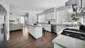 Una cocina moderna con armarios blancos, una isla central y una estufa integrada.
