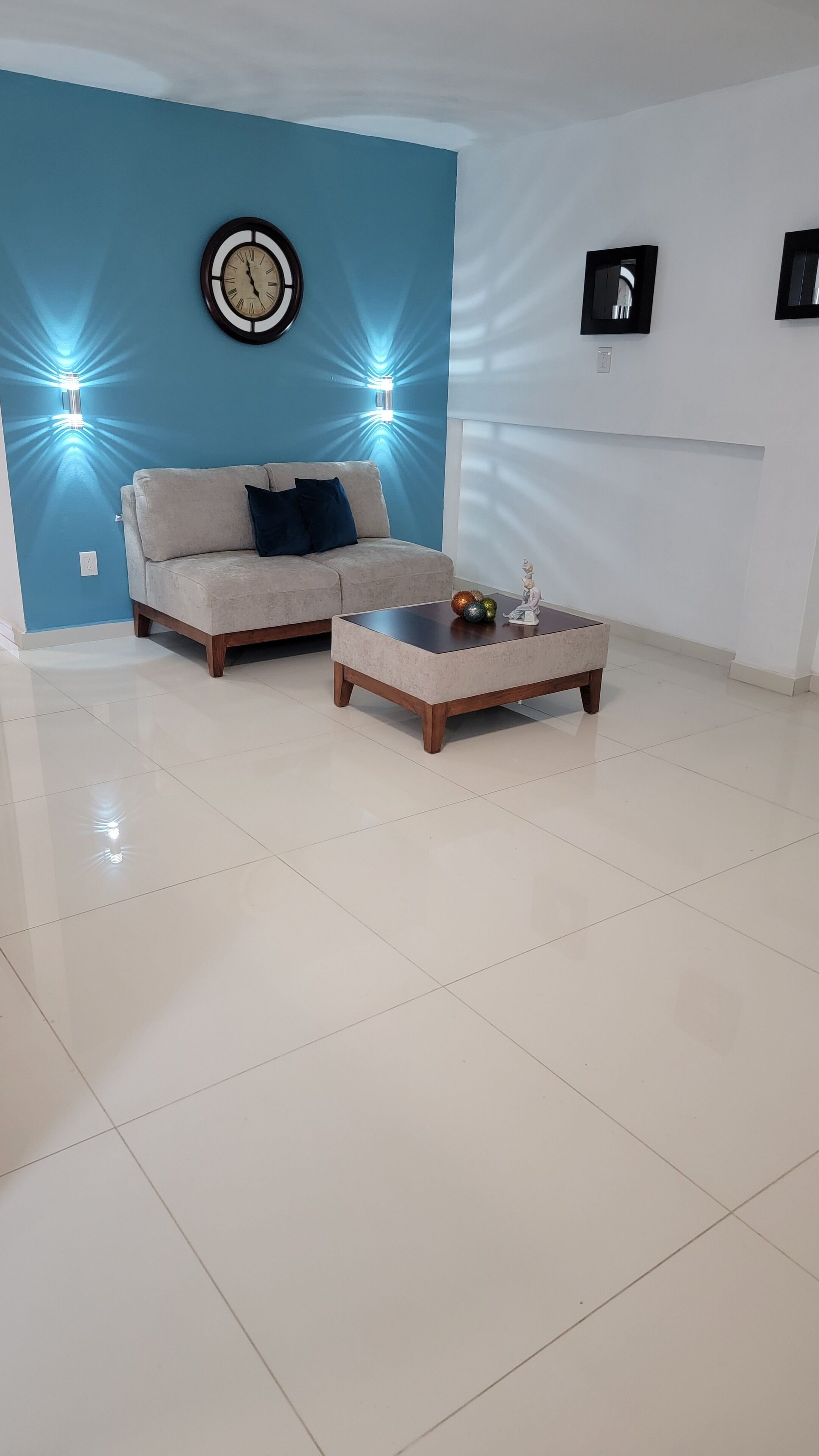 Una sala de estar con una pared azul decorativa, un sofá, una mesa de centro y un reloj de pared.