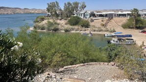 A lakeside property with a house, boats, and a patio area.