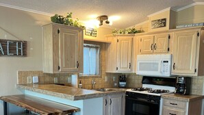 A kitchen with wooden cabinets, a built-in island, a microwave, a stove, and a coffee maker.