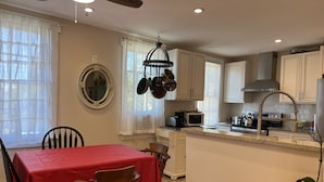 Une cuisine équipée d’une table à manger, de chaises, d’un ventilateur de plafond, d’un four à micro-ondes et de placards.