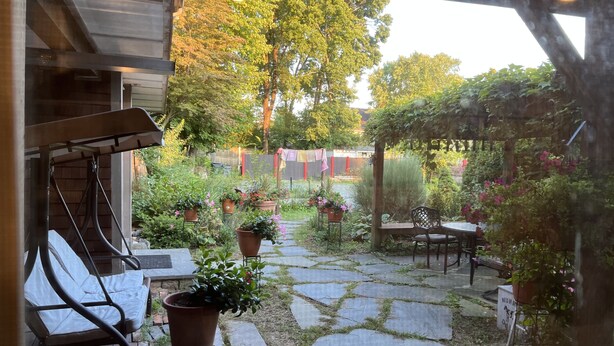 Un espace patio doté d’un sol carrelé en pierre, de plantes en pot et de mobilier d’extérieur.