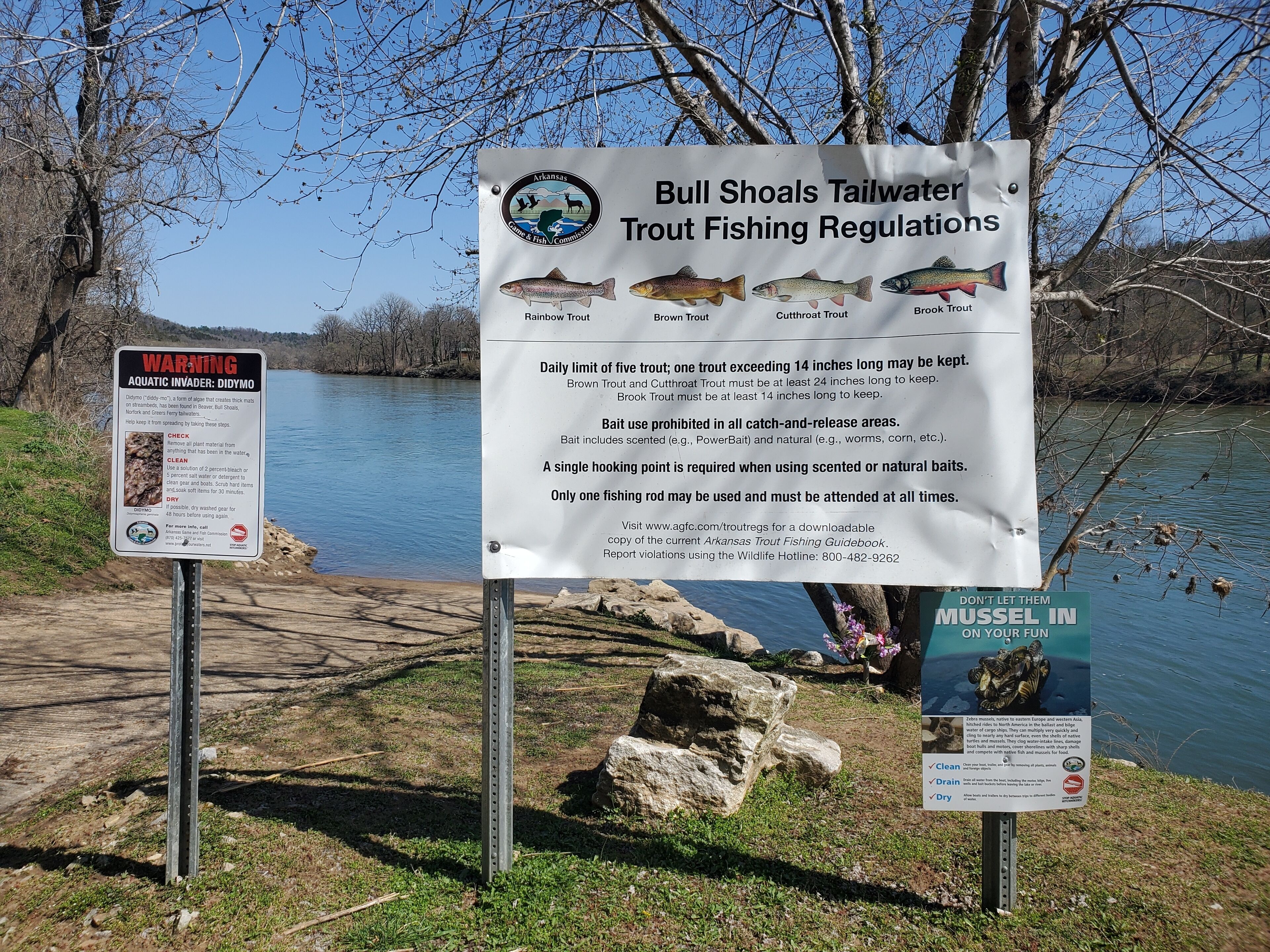 A fishing sign with regulations and a warning about aquatic invaders.