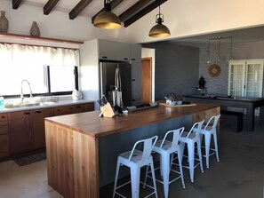 A modern kitchen with a central island, bar stools, a refrigerator, and pendant lighting. - Villa San Rafael En El Valle De Guadalupe, Bc (Valle de Guadalupe)